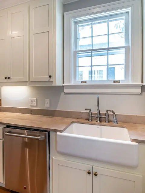 White shaker cabinet doors around a farmhouse sink under a bright window