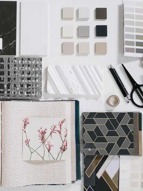 Tile, stone, fabric and paint samples laid out with scissors and a pen for a kitchen design