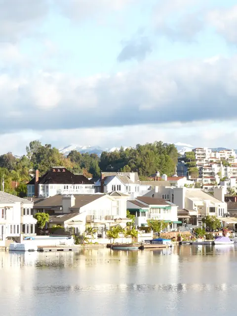 Homes along the shore of Lake Mission Viejo under a bright sky